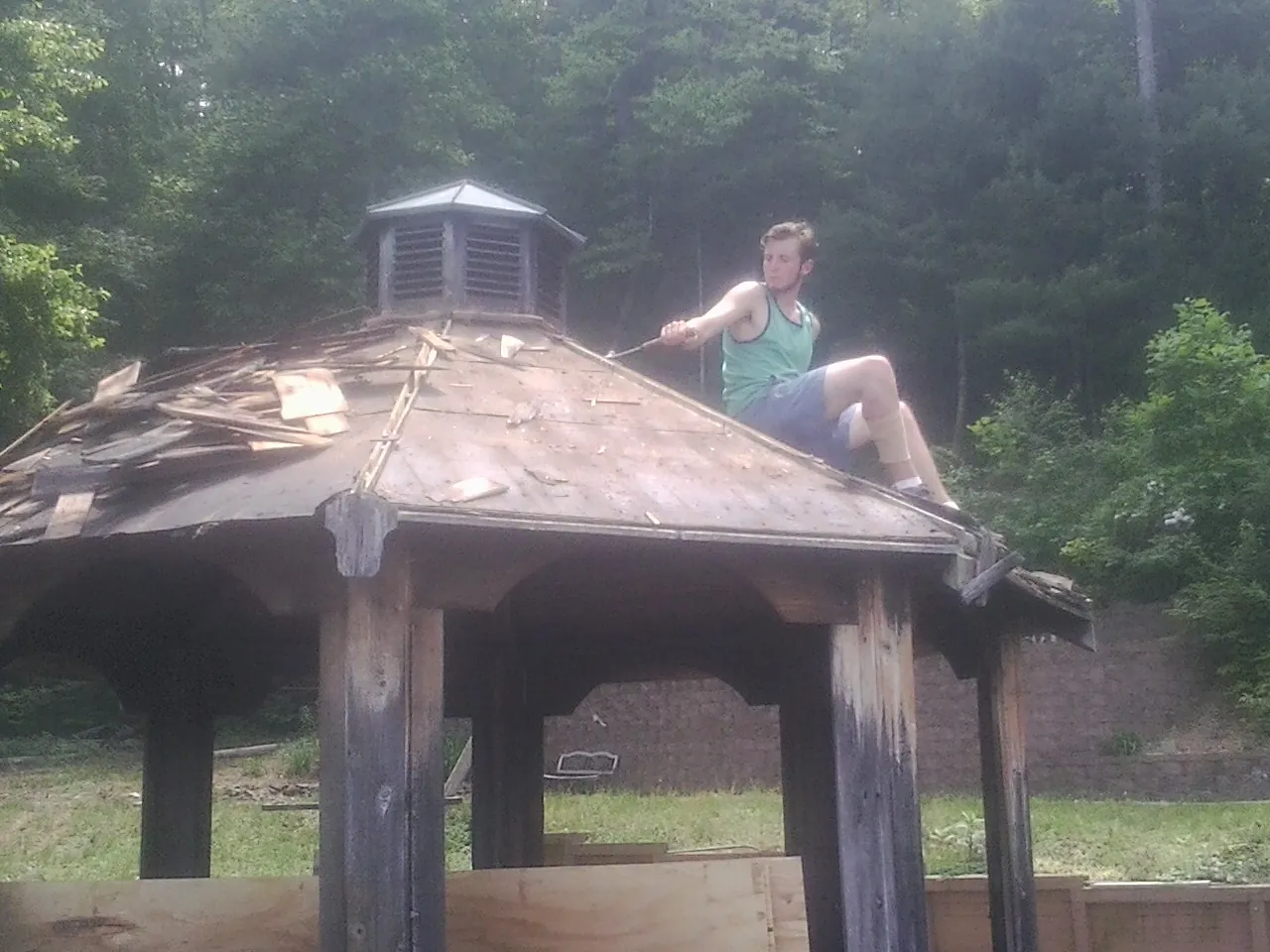 Tearing the old roof off a wooden gazebo before new shakes in Swisshome