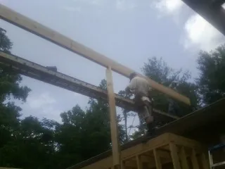 Carpenter setting a ridge beam over a new addition frame — Ice Dam Removal by Roofing Brothers in Swisshome