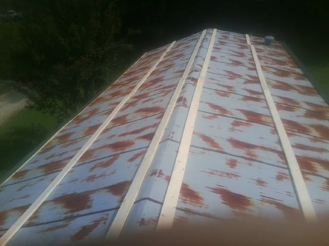Rusted metal roof panels with new wood purlins before replacement — Storm Damage Roof Repair in Swisshome by Roofing Brothers