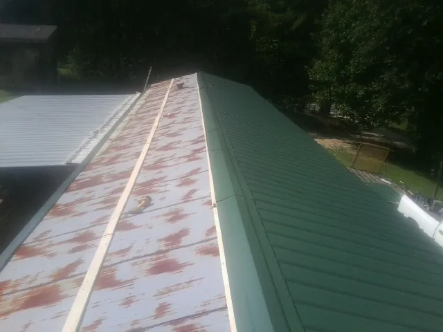 Old rusted panels beside newly installed green metal roofing — Wind Damage Roof Repair by Roofing Brothers in Swisshome