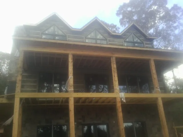 Dormers and porch framing on a large log home under construction — Roof Coating work by our crew in Swisshome