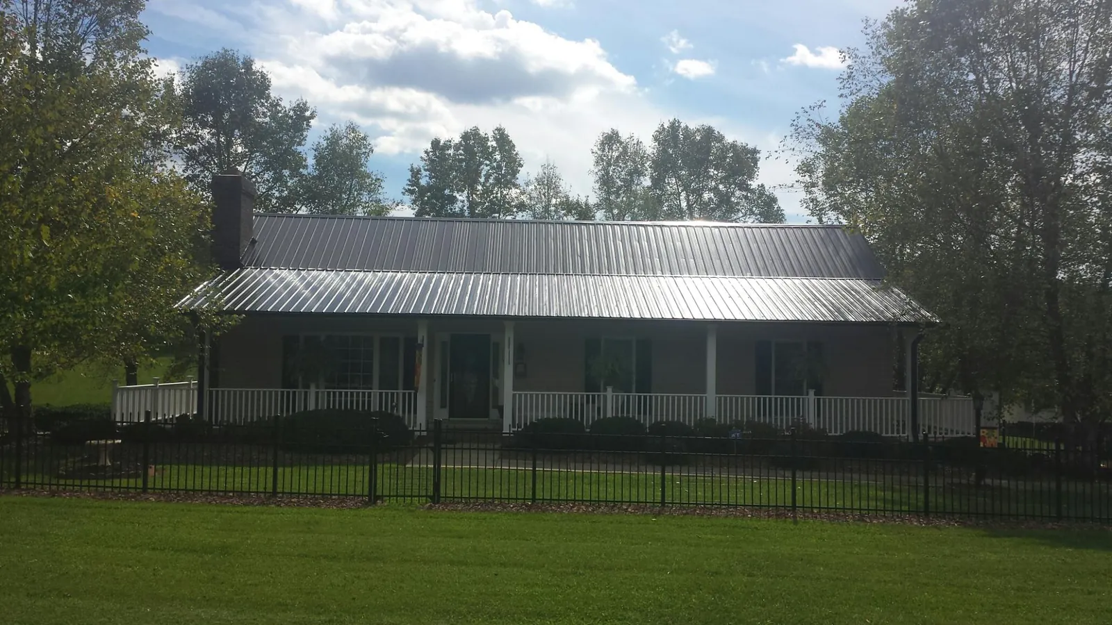 Gray metal roof on a brick ranch with a full width front porch — Gutter Guard Installation work by our crew in Swisshome