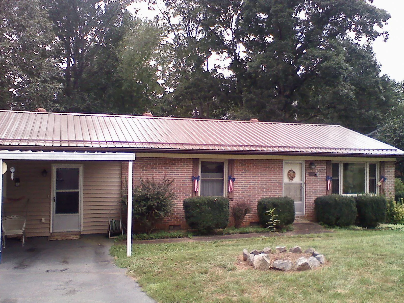 Bronze metal roof and carport on a brick ranch home — Roof Repair work by our crew in Swisshome