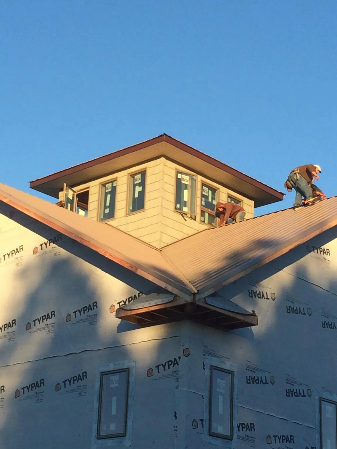 Roofers working around a rooftop cupola on a new metal roof at sunset — Roof Waterproofing in Swisshome by Roofing Brothers